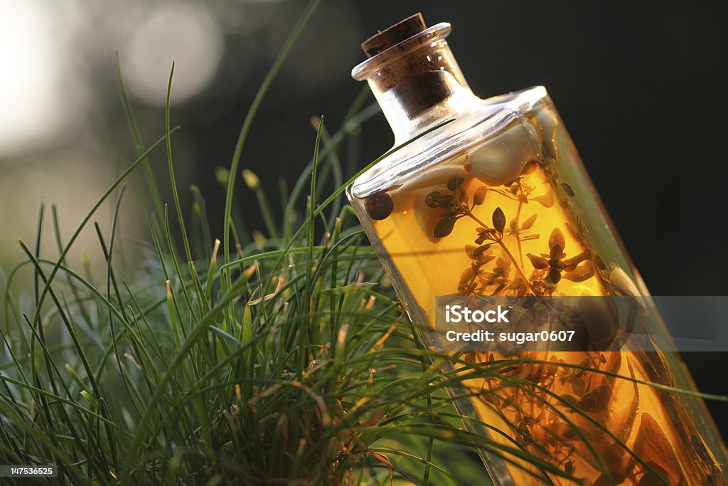 Herbal vinegar Herbal vinegar with floating herbs in a glass bottle, homemade. Aromatherapy Stock Photo