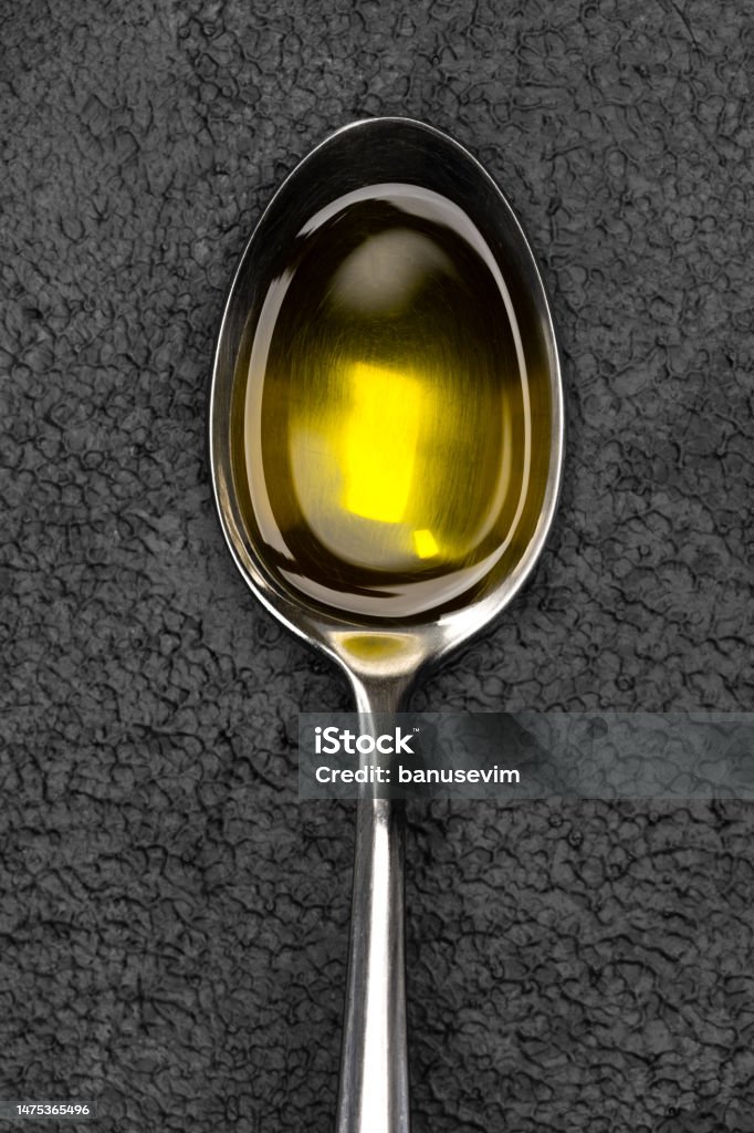 A spoonful of organic olive oil on vintage background Spoon Stock Photo