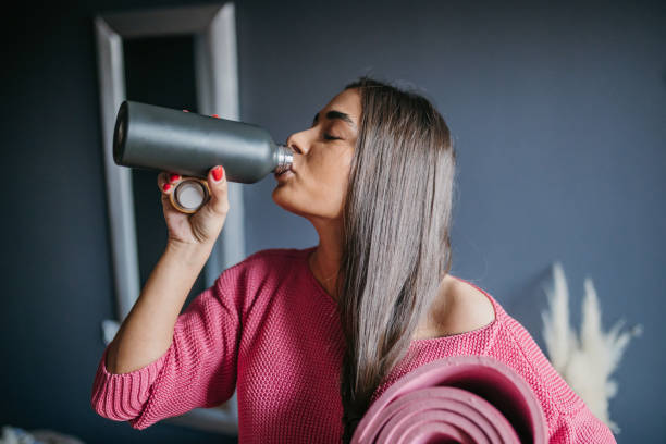 istock Young beautiful woman drinks water after home workout 1475366127