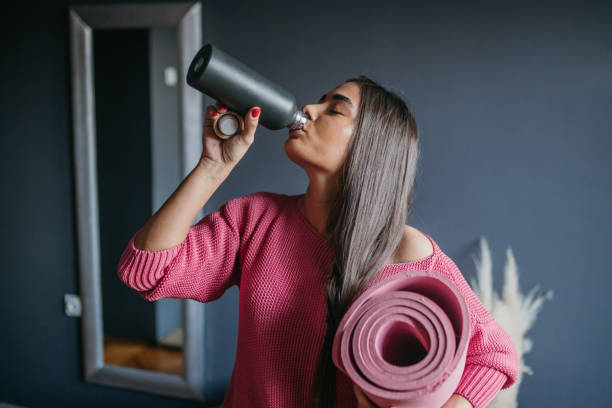 istock Young beautiful woman drinks water after home workout 1475367493