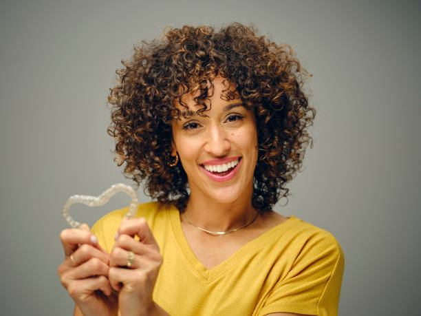 눈에 띄지 않는 치아 교정 장치를 들고 있는 행복한 젊은 여자 스톡 사진