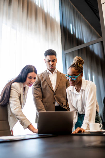 Three young entrepreneurs seen in a meeting room during working hours stock photo