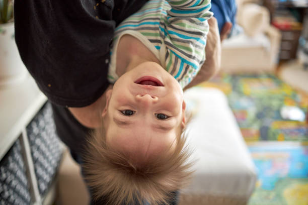 Little boy cute child  baby playing with his father, hanging upside down. stock photo