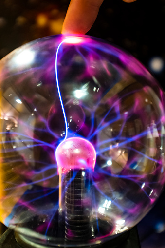 Electricity lighting ray going to a finger hand on a powerful spark sphere close up