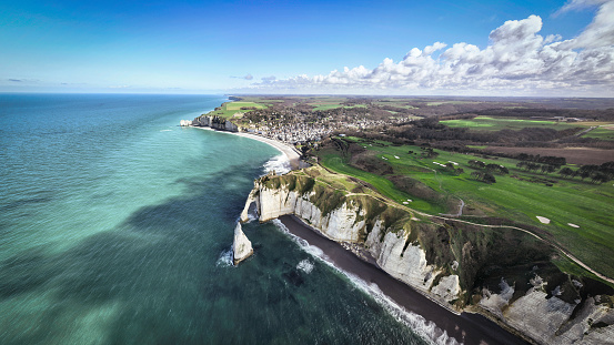 Aerial view of the famous Chalk Cliffs of Etretat - Falaises d’Étretat with Failaise D’Aval Needle and Natural Arch at the Normandy Alabaster Coast under sunny skyscape. Drone Point of View stitched XXL Panorama. Étretat, Seine-Maritime, Le Havre, Normandy, France, Europe