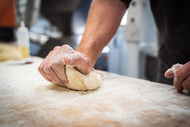 istock Hands kneading dough on a wooden table with flour 1475379029