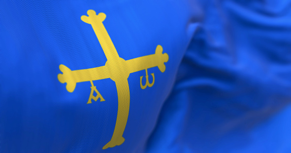 The Asturias flag waving. Autonomous community in northern Spain. Blue with golden victory cross shifted towards the hoist side. Selective focus. 3d illustration render. Close-up. Textured background