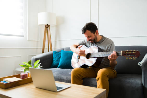 istock Cheerful man learning to play the guitar at home 1475394110
