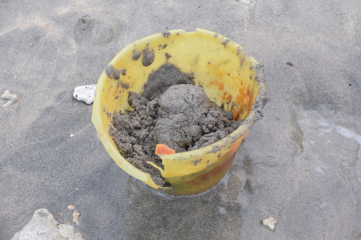 Broken bucket full of wet sand