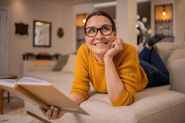 istock Woman reading book at home 1475397888