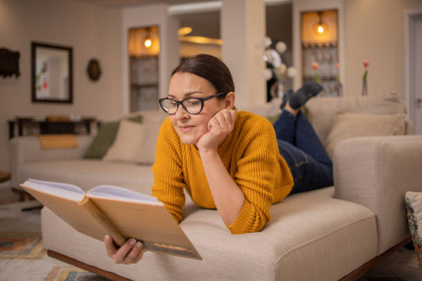 Woman reading book at home stock photo