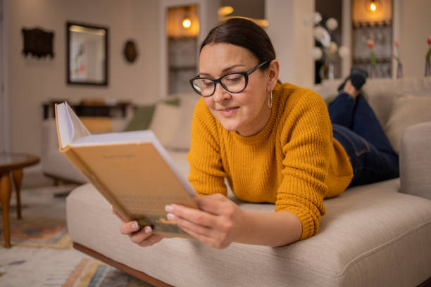istock Woman reading book at home 1475397891