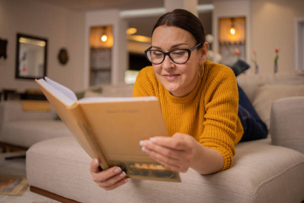 istock Woman reading book at home 1475397894