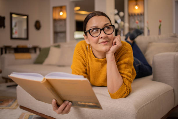 istock Woman reading book at home 1475397897