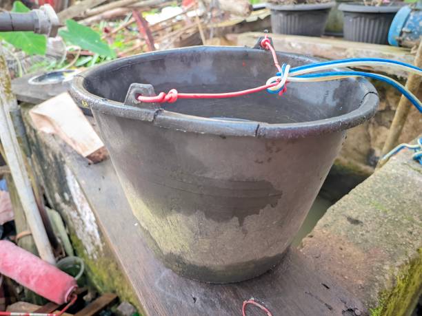 istock an old black plastic bucket filled with well water with a handle attached to it with a cable 1475400887