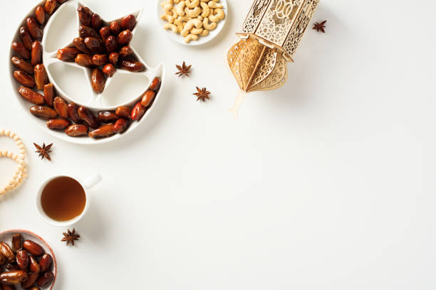 istock Ramadan concept. Crescent and star plate with dried dates, islamic lantern, cup of tea, nuts, rosary breads on white background. 1475401328