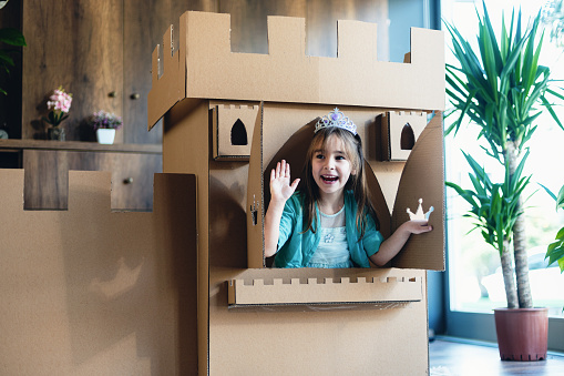 Cute Little Princess Playing Role Play Game At Home With Castle Made Of Cardboard