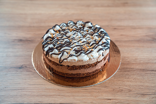 A close-up of a professionally made cake with layers of chocolate filling, cream coating and sponge dough. High angle shot. Full length image.