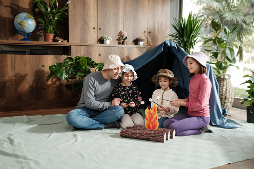 Family as father with three children playing camping game at home, concept for activities for activities at home for children