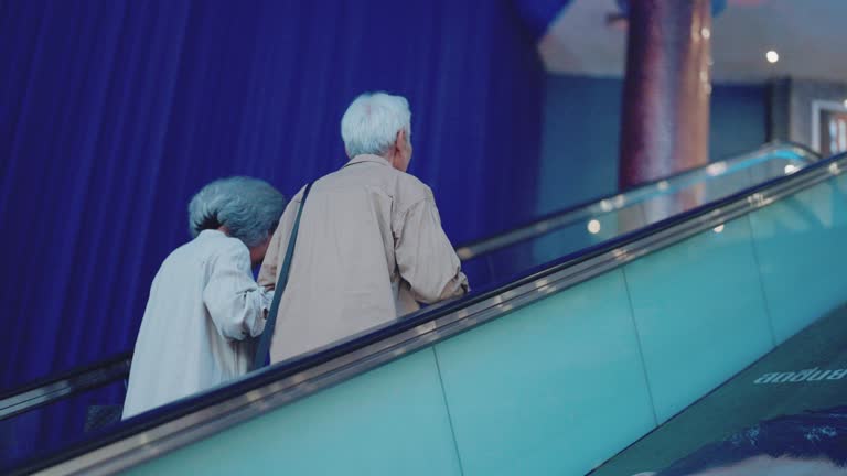 Elderly man and woman chattering on the escalator going up to the cinema.