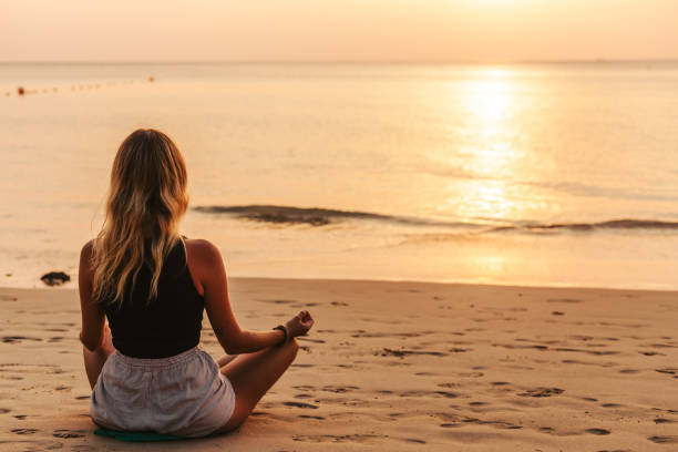 istock Young woman practicing yoga on the beach 1475414422