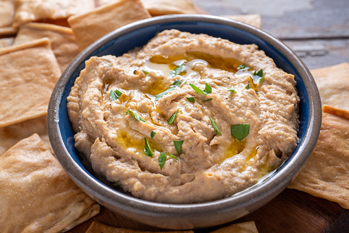 bowl with hummus, ingredients and slices of pita