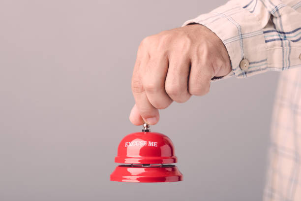 istock Close up hand holding the red call bell or service bell ring on grey wall background. For hotel or restaurant advertising concept 1475418016