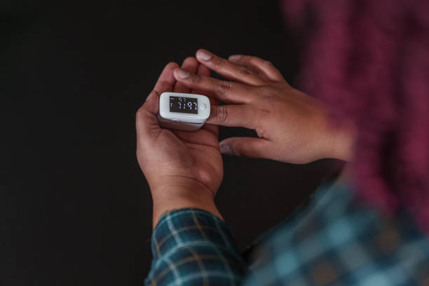 woman checking blood oxygen levels with finger pulse oximeter - taking pulse oximeter medical oxygen equipment human lung imagens e fotografias de stock