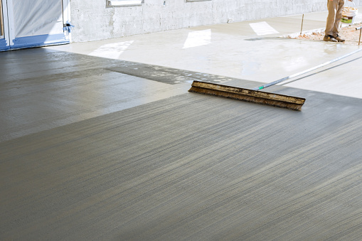 An employee of construction company uses broom to surface of fresh wet concrete cause groove texture pattern appear