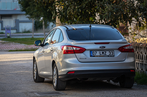 Side, Turkey – February 13 2023:         silver  Ford Focus  is parked  on the street on a warm  day against the backdrop of a park, shop