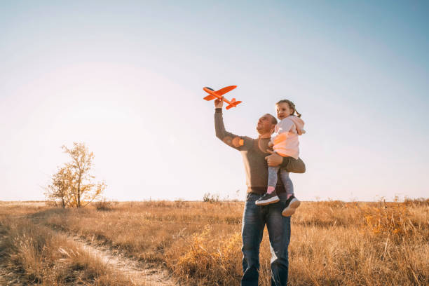 istock Happy Father And Child Having Fun Playing Outdoors. Smiling Young Dad And Daughter Spending Time Together, let an airplane into the sky 1475433963