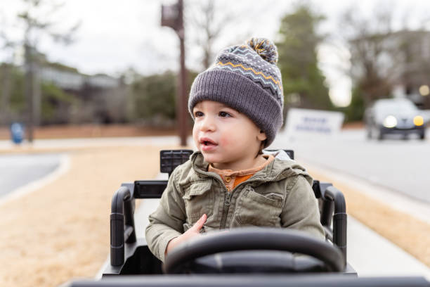 Asian boy driving a bulldozer and practices using his arm muscles to scoop sand while playing.
