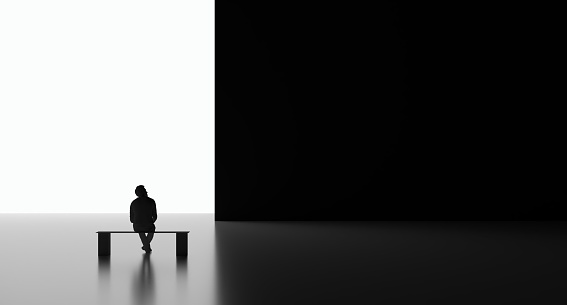 Isolated person sitting contemplating lonely thinking black and white