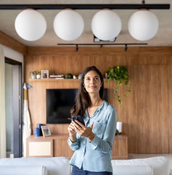 Woman controlling a lamp in her house using an automated system