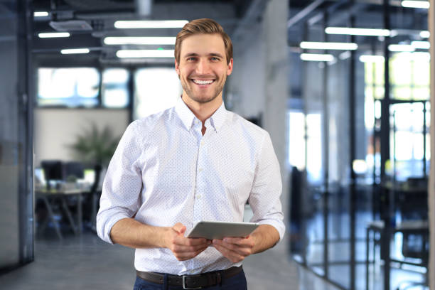 istock Handsome young businessman standing in modern office. 1475444851