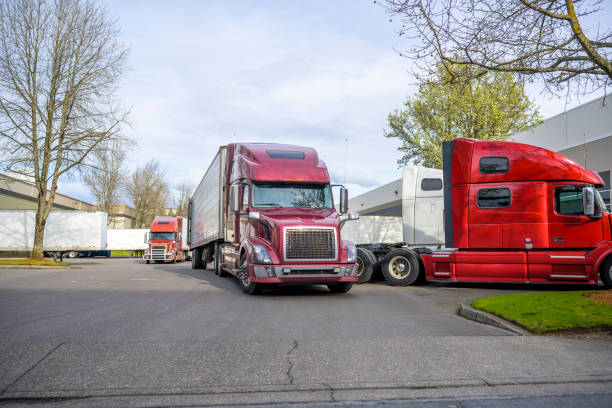 Warehouse parking lot filled with big rig semi trucks with refrigerator semi trailers loaded during a busy working day stock photo