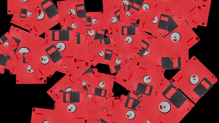 Red floppy disc in abstract explosion flying in different directions on a black background. simple colorful food animation concept with fruits