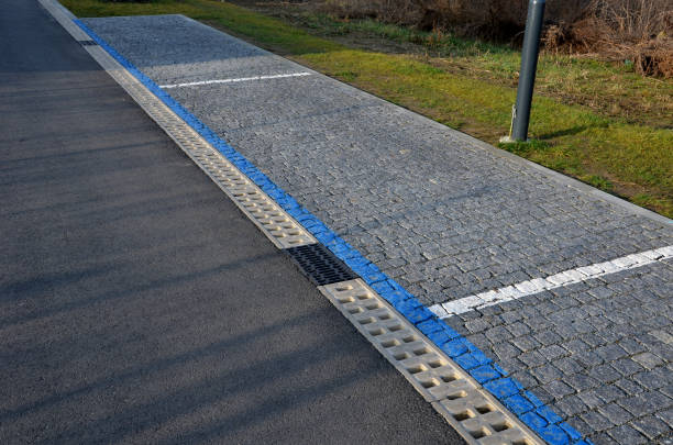 istock across the path there is a channel with a metal grid for drainage interlocking paving. the water is drained from the surface into the gutter and further into the rain sewer, blue line, parking zone 1475450183