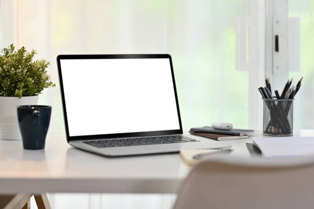 istock Laptop computer, coffee cup, books and houseplant on white table. Blank screen for your advertising text message. 1475453118