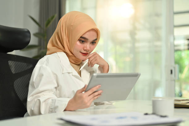 istock Gorgeous Muslim woman using digital tablet, remote working, searching on web at comfortable workplace. 1475454023