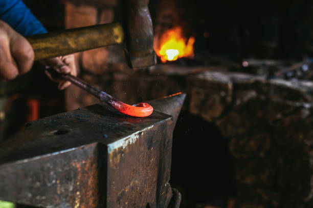 istock Blacksmith manually forging the molten metal on the anvil in smithy with spark fireworks, close up 1475454216