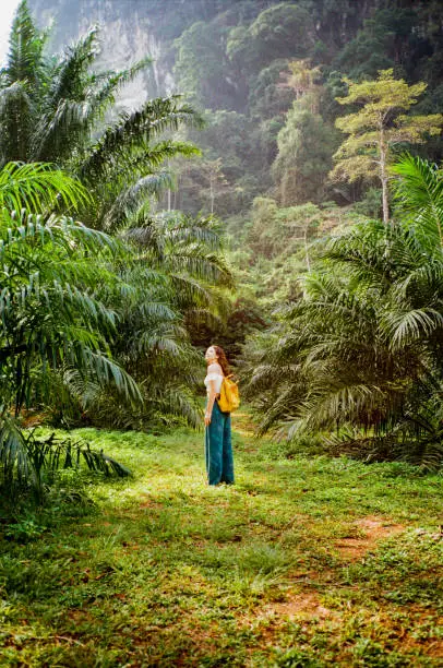 Young Caucasian woman walking on the path through the jungles