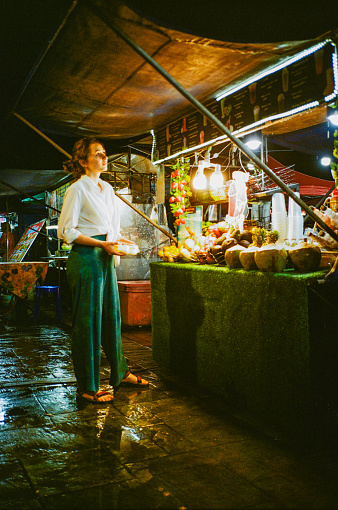 Young woman  standing on night market. Shot with flashlight