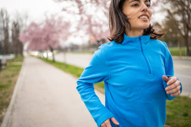 A young woman, an athlete, is jogging on a path in the park in a beautiful spring environment, she is dressed in a sports wardrobe