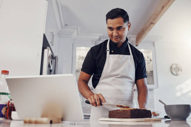 Man, tablet and baking cake recipe in kitchen for birthday party or celebration. Young chef, reading cooking website and bake dessert product on counter for wellness on digital tech device