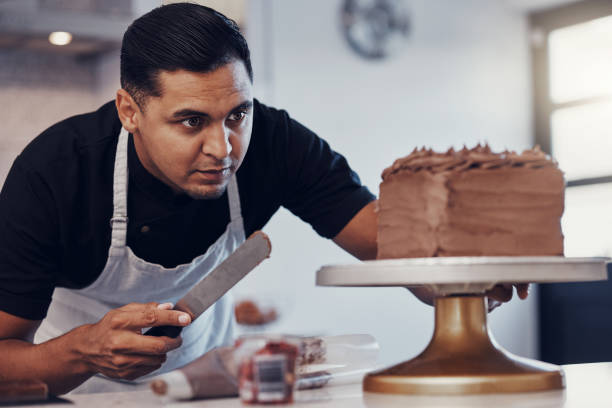 istock Baking, kitchen and man icing cake with chocolate frosting and piping bag in bakery with focus and skill. Sweets, small business and baker decorating dessert for birthday event and working from home. 1475462677