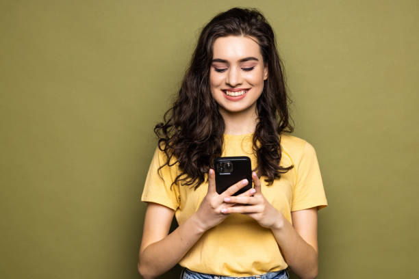 istock Young woman hold in hand use mobile cell phone typing read message isolated on khaki background 1475463697