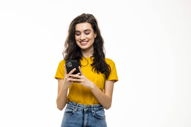 istock Young brunette woman smiling while using phone isolated over white background 1475463875