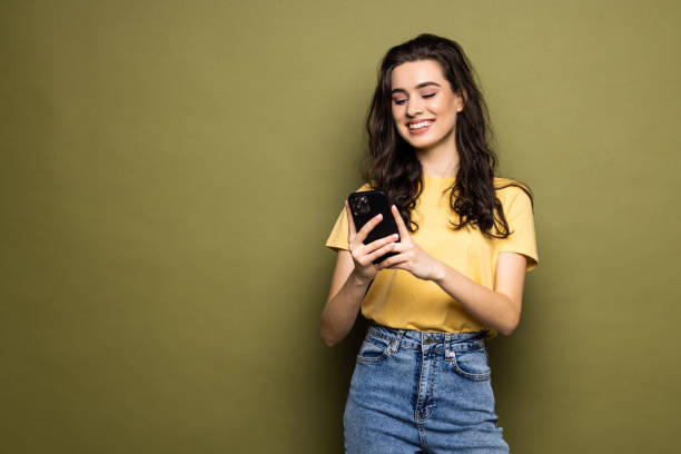 istock Young woman hold in hand use mobile cell phone typing read message isolated on khaki background 1475463924
