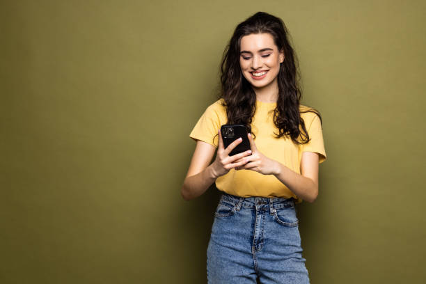istock Young woman hold in hand use mobile cell phone typing read message isolated on khaki background 1475463945